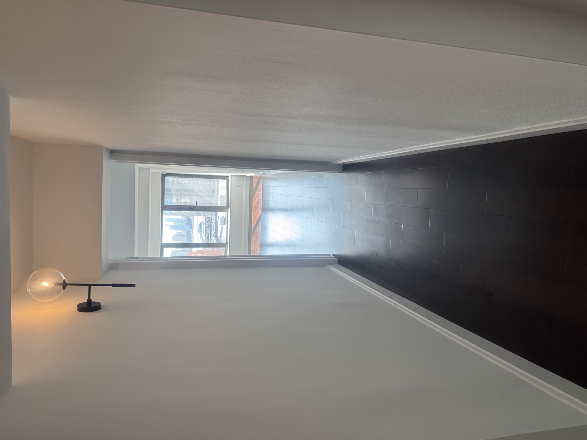 Renovated room with contrasting subway-tile accent wall and modern lamp